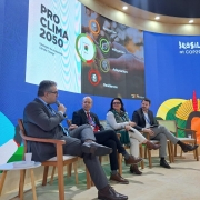 na imagem, há um painel atrás com a marca do proclima. na frente, em cima do palco, integrantes do RS olham para o moderador.