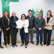 Representantes da Sema, Fepam e Corsan na entrega das seis licenças ao empreendimento. A secretária e a representante da Corsan seguram os documentos. Há oito pessoas na foto, representando as três instituições. 