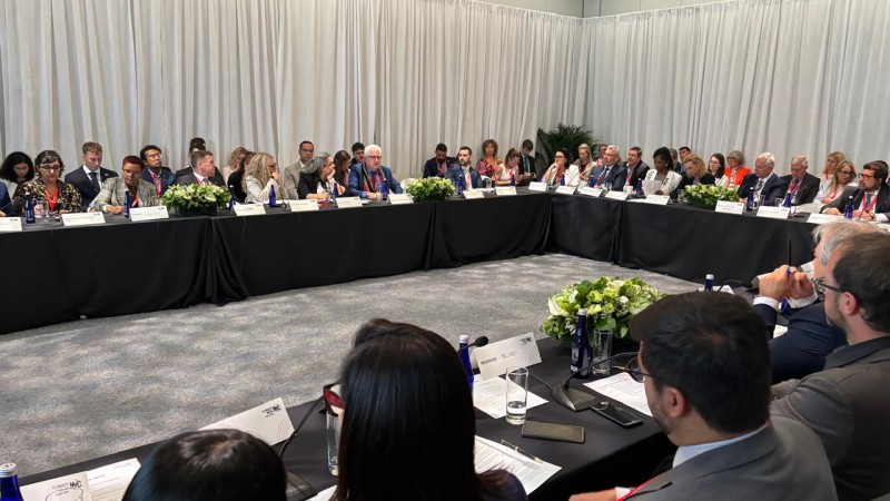 na imagem, uma sala com uma mesa em forma to U e l&iacute;deres mundiais reunidos em evento da coaliz&atilde;o under 2