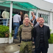 Dois homens posam em frente à nova sede regional Sema-Fepam, em Passo Fundo. Atrás deles, diversas outras pessoas confraternizam.